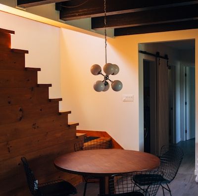 round brown wooden table and chairs under white pendant lamp