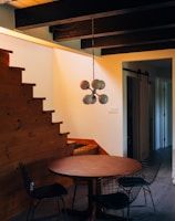 round brown wooden table and chairs under white pendant lamp